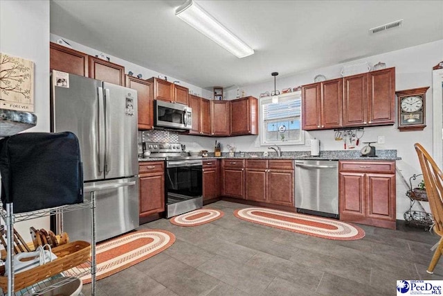 kitchen with a sink, visible vents, appliances with stainless steel finishes, dark countertops, and pendant lighting