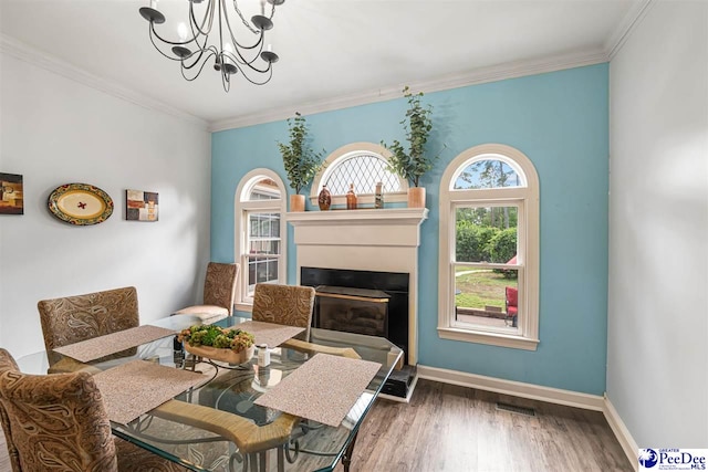 4128 W Pelican Ln, Florence, SC 29501 - dining space with a chandelier, crown molding, wood finished floors, baseboards, and a glass covered fireplace