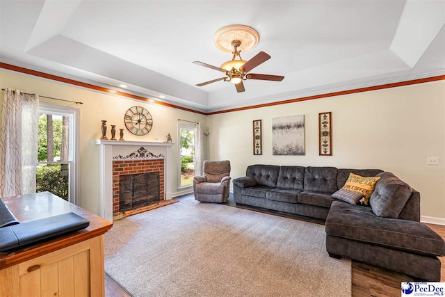4128 W Pelican Ln, Florence, SC 29501 - living room featuring a tray ceiling, a fireplace, ceiling fan, and wood finished floors