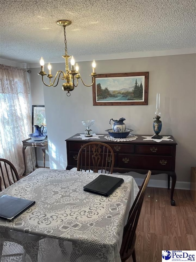 dining area with baseboards, a textured ceiling, an inviting chandelier, and wood finished floors