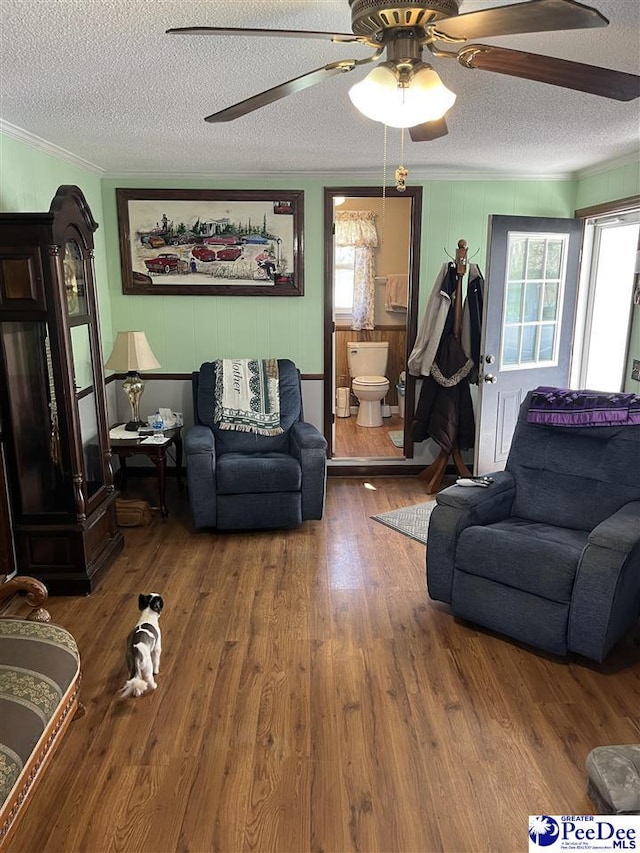 living room with ornamental molding, a textured ceiling, and wood finished floors