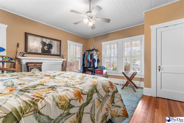 bedroom with multiple windows, crown molding, a brick fireplace, and wood-type flooring