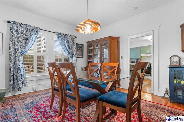 dining room with crown molding, a chandelier, and light wood-type flooring