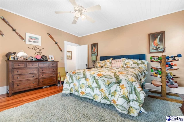 bedroom with wood-type flooring, ornamental molding, and ceiling fan