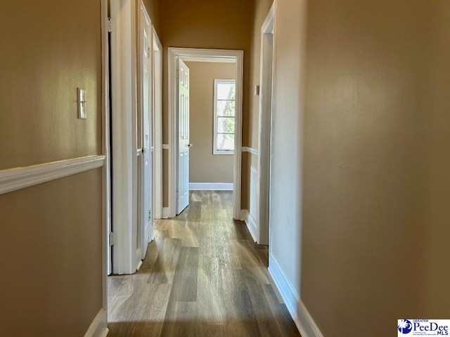 hallway featuring wood finished floors and baseboards