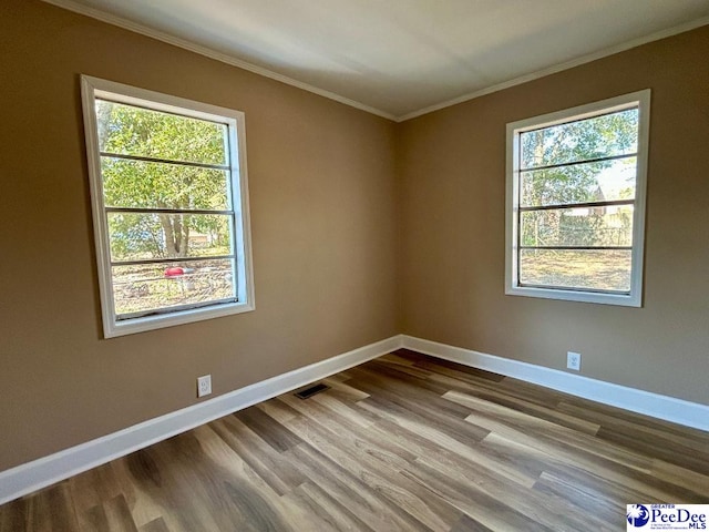 unfurnished room with a wealth of natural light, ornamental molding, visible vents, and baseboards