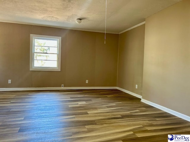 spare room with a textured ceiling, baseboards, wood finished floors, and crown molding