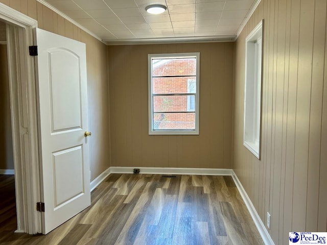 spare room with baseboards, wood finished floors, and ornamental molding