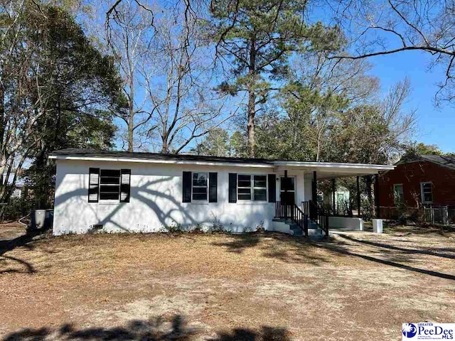 view of front facade with dirt driveway, an attached carport, and covered porch