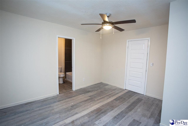 unfurnished room with a textured ceiling, wood finished floors, a ceiling fan, and baseboards