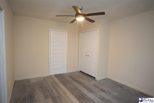 unfurnished bedroom featuring a closet, ceiling fan, baseboards, and wood finished floors