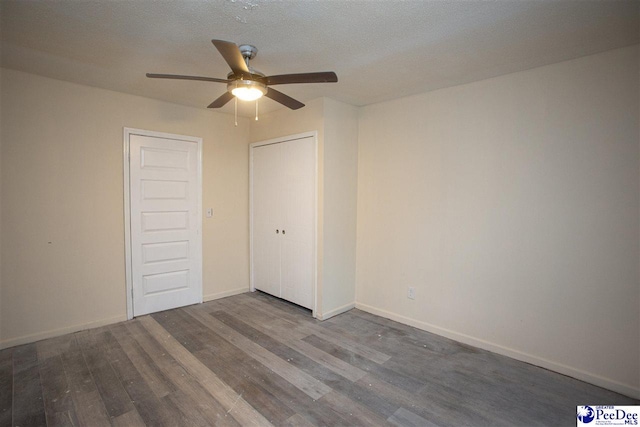 unfurnished bedroom with ceiling fan, a textured ceiling, baseboards, and wood finished floors