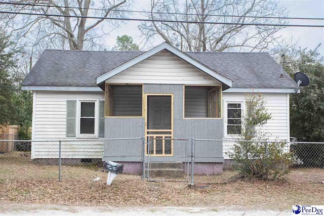 bungalow with a fenced front yard, crawl space, and roof with shingles