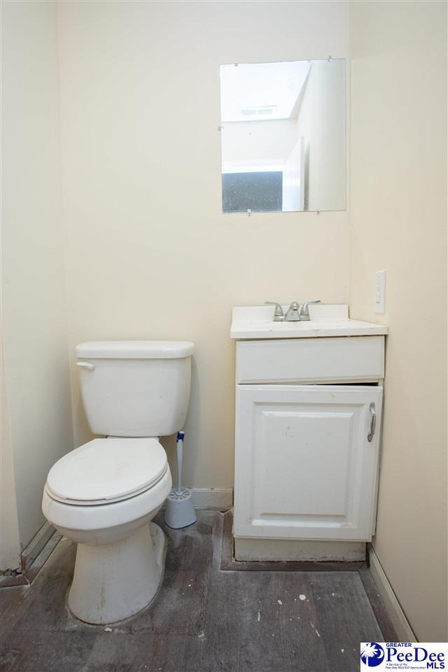 half bathroom with toilet, baseboards, and vanity