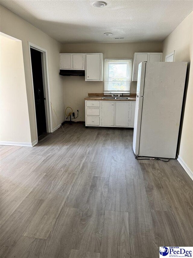 133 W Washington St, Hartsville, SC 29550 - kitchen featuring white cabinetry, freestanding refrigerator, wood finished floors, and a textured ceiling
