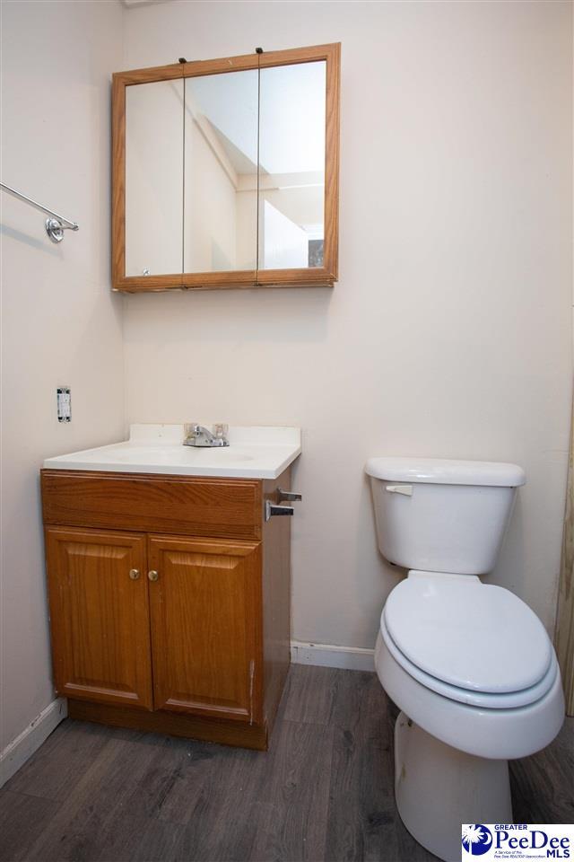 bathroom with baseboards, vanity, toilet, and wood finished floors