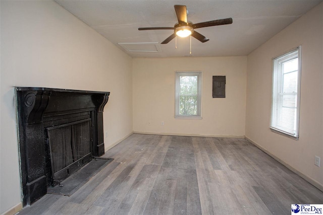 unfurnished living room featuring attic access, electric panel, baseboards, wood finished floors, and a fireplace