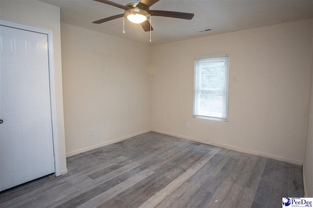 empty room with baseboards, visible vents, ceiling fan, and wood finished floors