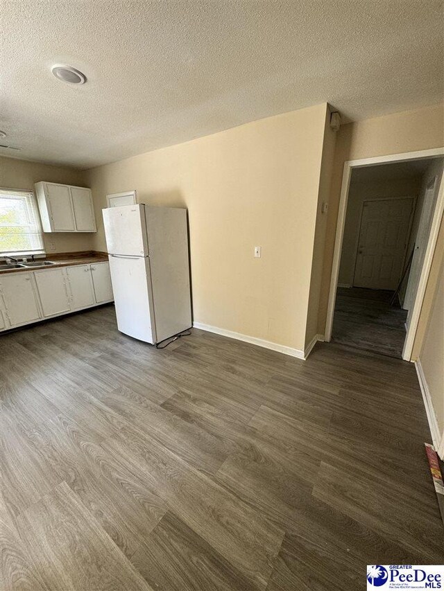 133 W Washington St, Hartsville, SC 29550 - unfurnished dining area featuring a sink, baseboards, a textured ceiling, and dark wood-style floors