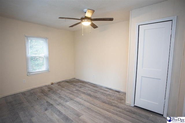 spare room featuring ceiling fan, baseboards, and wood finished floors