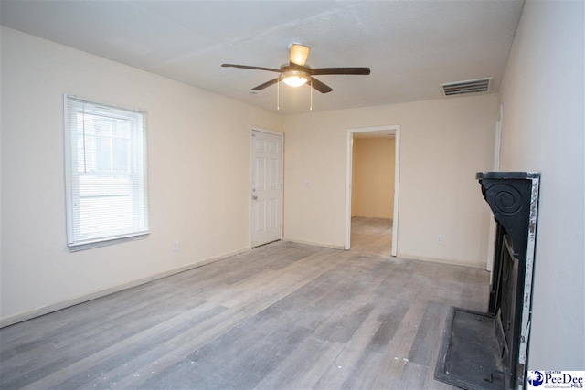 interior space featuring baseboards, visible vents, ceiling fan, and light wood finished floors