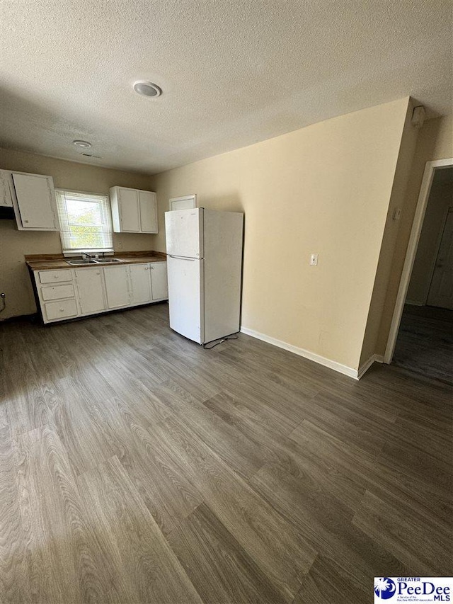 133 W Washington St, Hartsville, SC 29550 - kitchen with a textured ceiling, white cabinetry, freestanding refrigerator, and dark wood finished floors