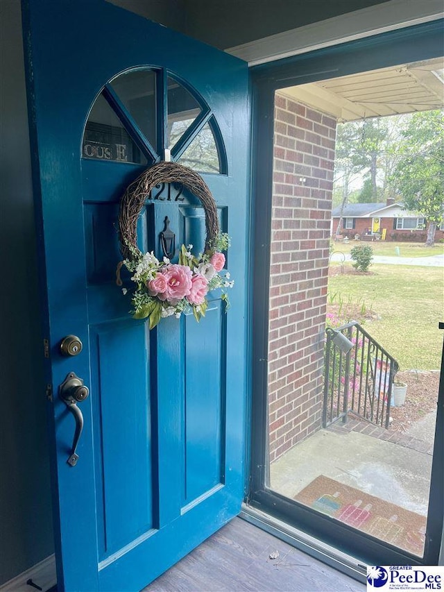 doorway to property featuring a yard and brick siding