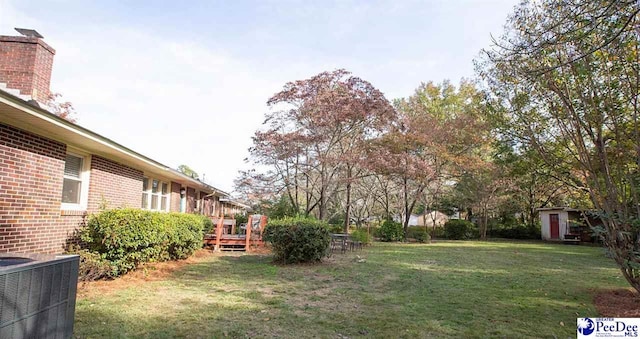 view of yard featuring central AC unit, a storage shed, an outdoor structure, and a deck