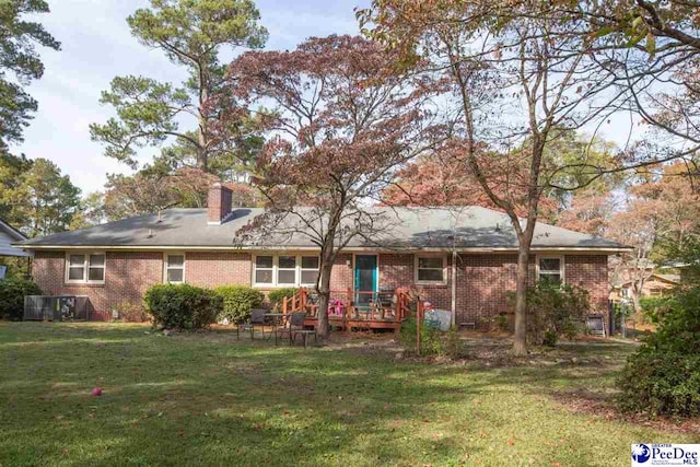 back of house with a chimney, a yard, and brick siding