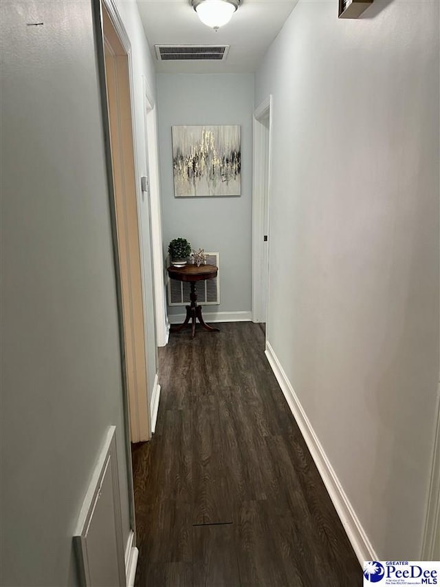 hall featuring baseboards, dark wood finished floors, and visible vents