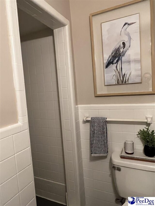 bathroom featuring a wainscoted wall, tile walls, and toilet