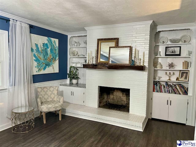 sitting room featuring dark wood-style flooring, built in features, ornamental molding, a textured ceiling, and a brick fireplace