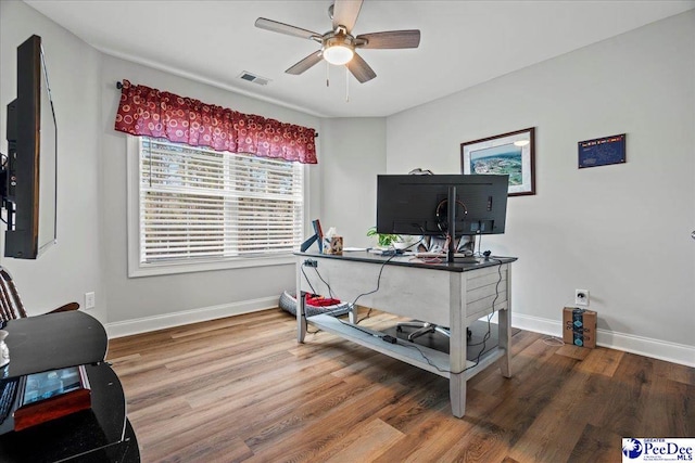 office space with visible vents, ceiling fan, baseboards, and wood finished floors