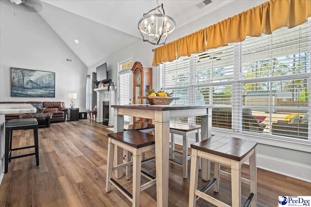 dining space featuring a chandelier, visible vents, a fireplace, and wood finished floors