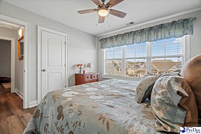 bedroom featuring visible vents, a ceiling fan, baseboards, and wood finished floors