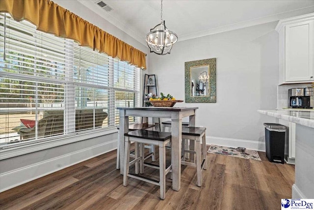 dining space featuring visible vents, dark wood-type flooring, ornamental molding, an inviting chandelier, and baseboards