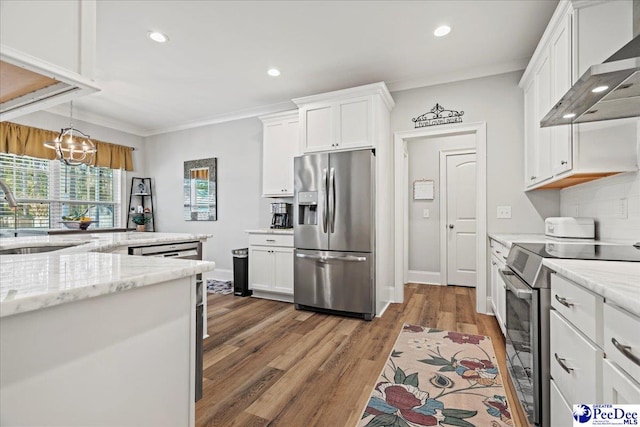 kitchen featuring white cabinets, stainless steel appliances, wall chimney range hood, and a sink