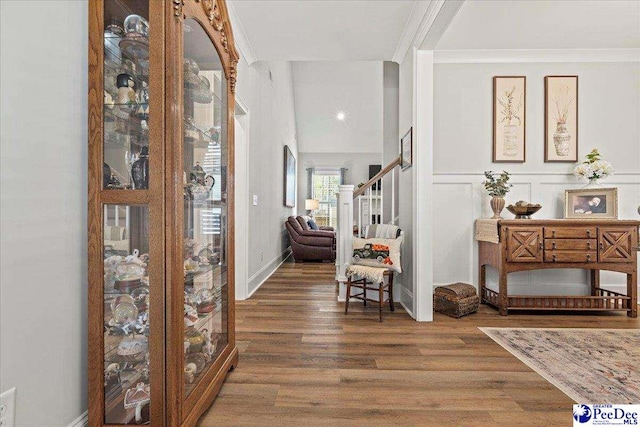 foyer entrance with stairway, wood finished floors, a decorative wall, and ornamental molding