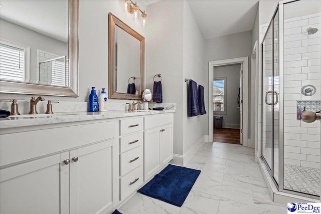 full bath featuring marble finish floor, a sink, a shower stall, double vanity, and baseboards