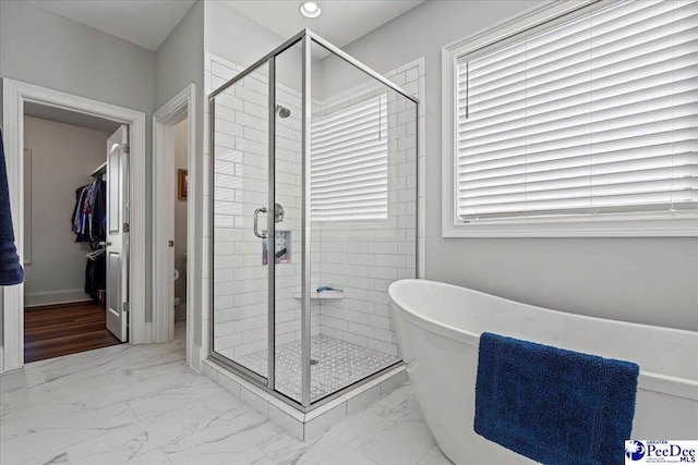 full bathroom featuring a freestanding tub, marble finish floor, and a shower stall