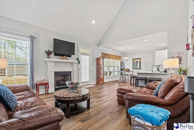 living room with recessed lighting, a fireplace, high vaulted ceiling, and light wood-style floors