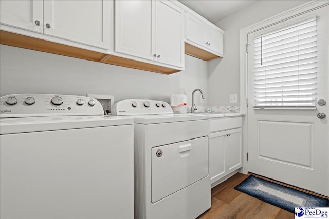 washroom with a sink, wood finished floors, cabinet space, and washing machine and clothes dryer