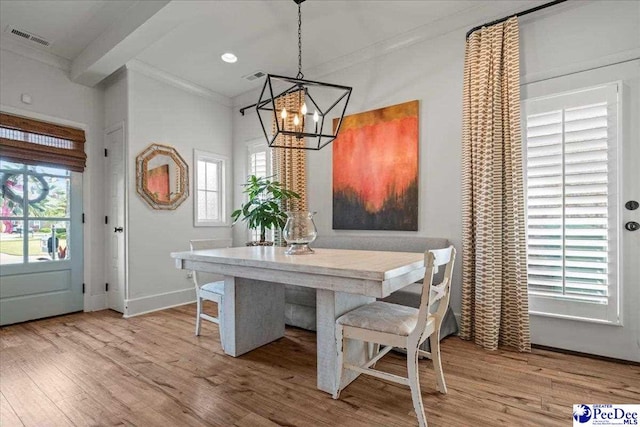 dining area with an inviting chandelier, wood finished floors, visible vents, crown molding, and baseboards