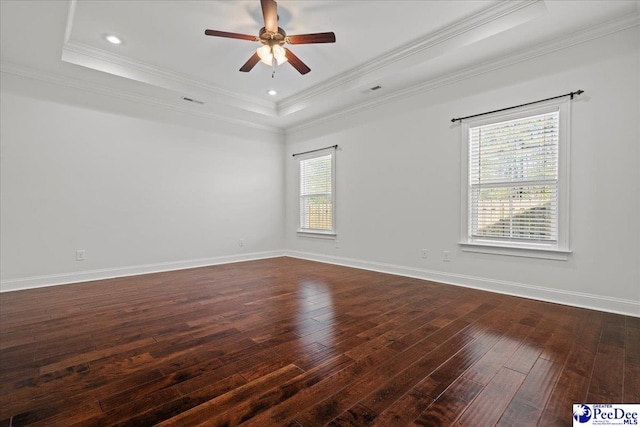 spare room with crown molding, a ceiling fan, a raised ceiling, dark wood finished floors, and baseboards