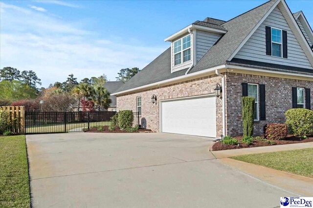 view of side of home with brick siding, fence, concrete driveway, and a shingled roof
