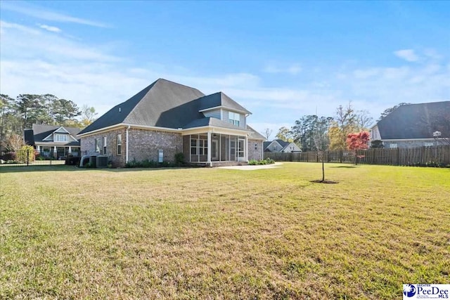 rear view of house with central air condition unit, a lawn, and fence