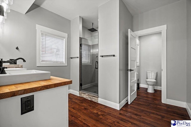 bathroom featuring hardwood / wood-style flooring, vanity, an enclosed shower, and toilet