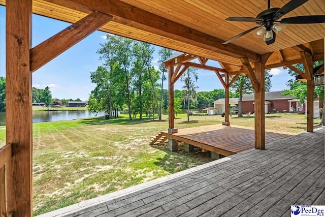 deck with a water view, ceiling fan, and a lawn