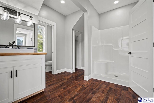 bathroom featuring wood-type flooring, a shower, vanity, and toilet