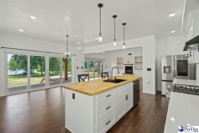 kitchen with butcher block counters, sink, pendant lighting, a kitchen island with sink, and white cabinets